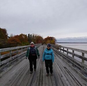 Two people walking along a boardwalk with the Dartmouth Volksmarch Club